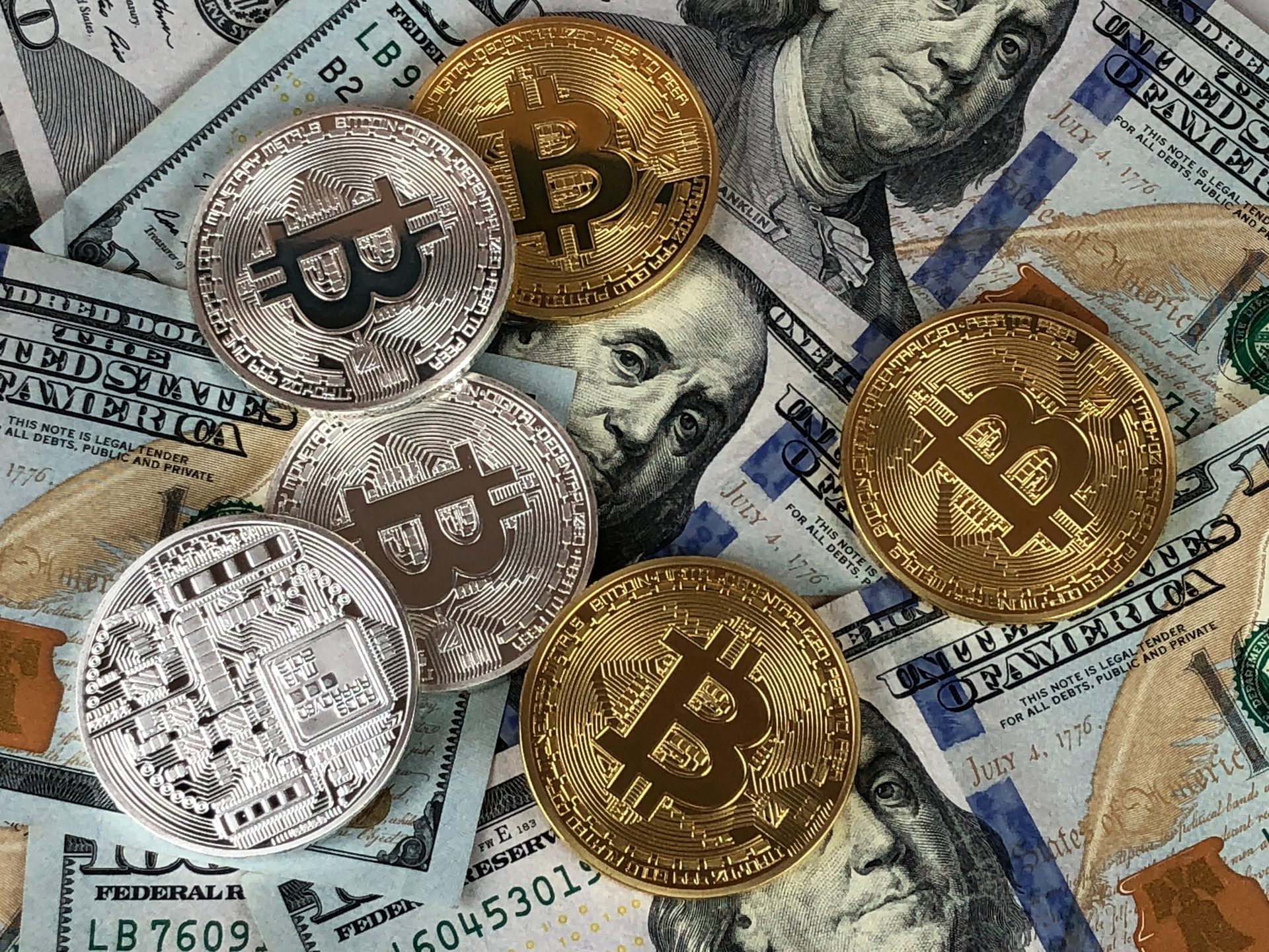 Some golden Bitcoins lying on a scattered US Dollar bills